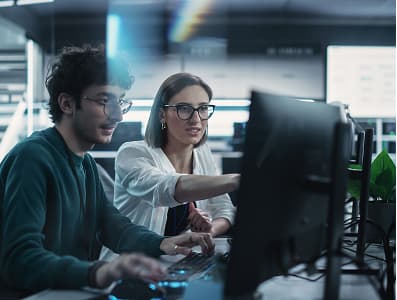 zwei Personen, die vor einem Computer diskutieren