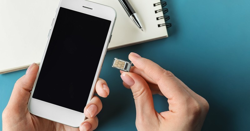 Die Person legt die SIM-Karte in ihr Handy ein.