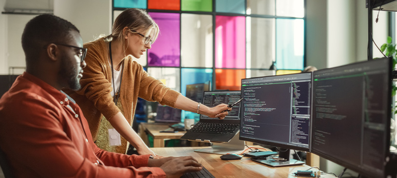 Mann und Frau unterhalten sich vor einem Monitor