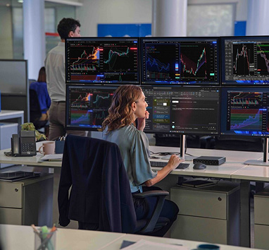 Eine Frau sitzt vor vielen Monitoren