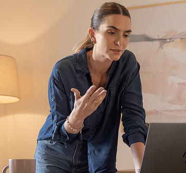 Eine frau steht und beugt sich sprechend zum Laptop