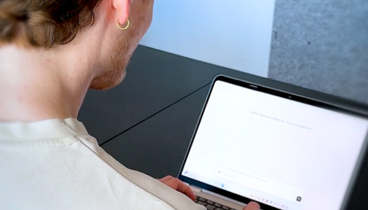 Blick &uuml;ber die Schuler eines Mannes. Er sitzt an einem Laptop.