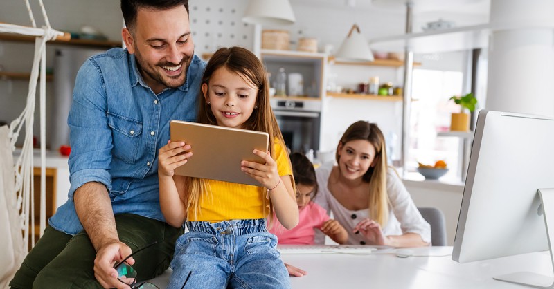 Eine glückliche Familie die Zeit zu Hause verbringt und digitale Technologiegeräte nutzt