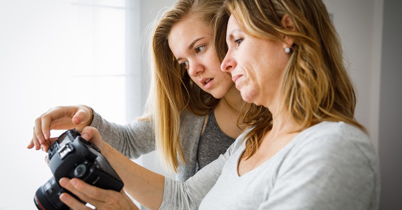 Mutter und Tochter machen Fotos und überprüfen sie mit einer modernen digitalen DSLR-Kamera