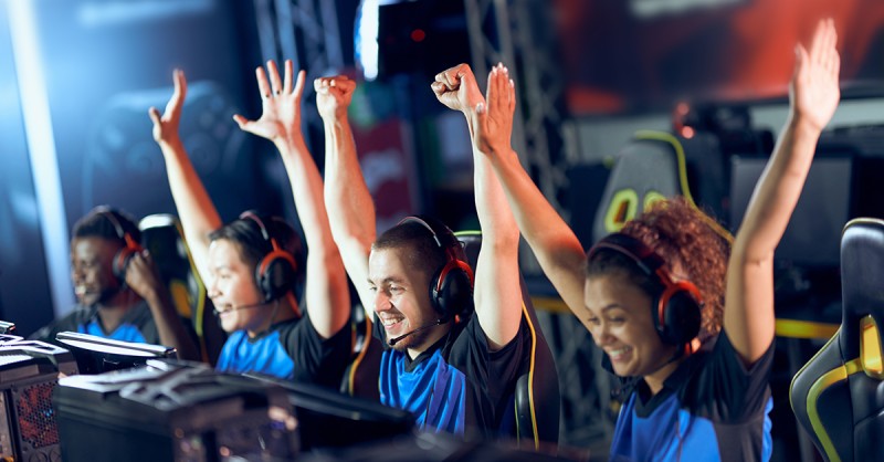 Team of happy professional cyber sport gamers celebrating success while participating in eSports tournament
