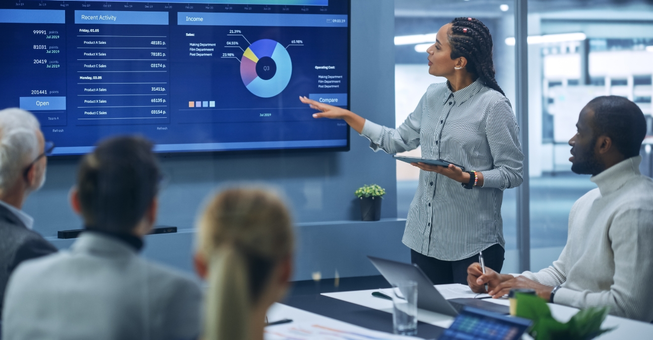 Woman presenting statistics to a group of people in a meeting room